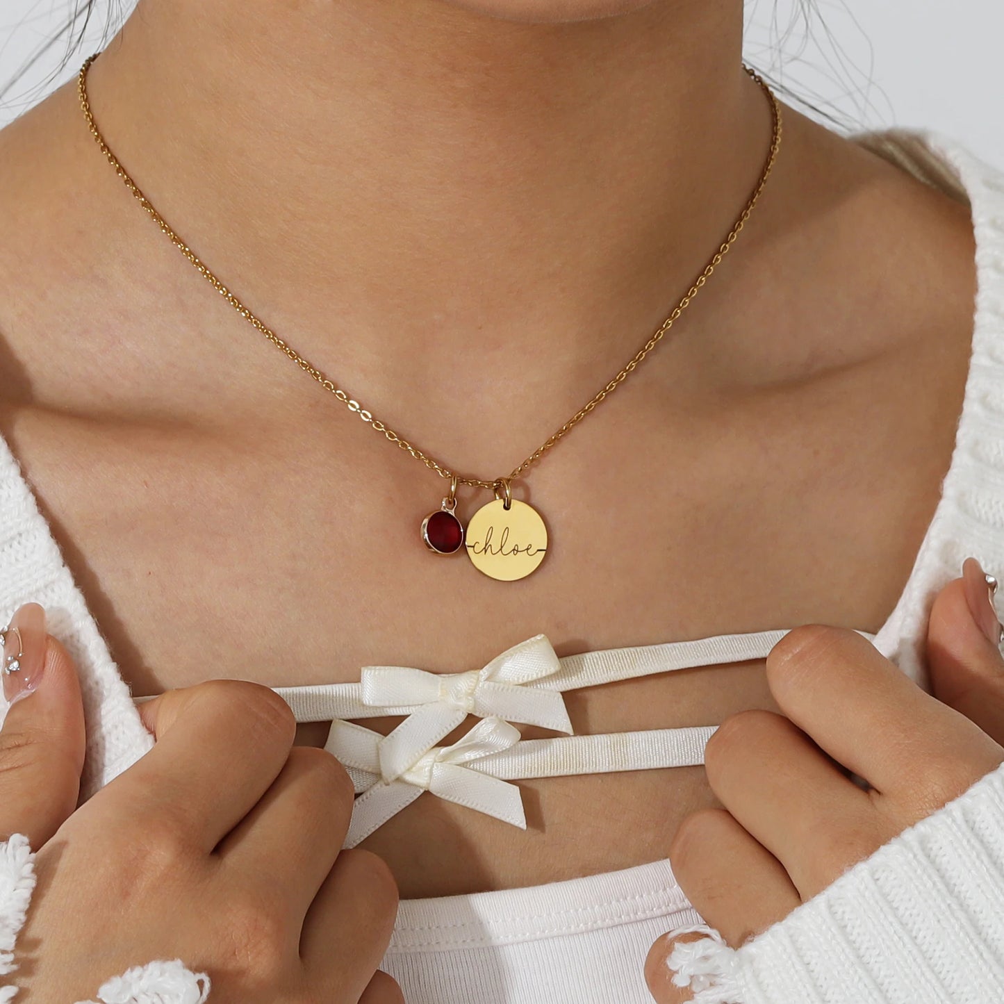 Collier médaillon personnalisé de couleur or avec prénom gravé et pierre de naissance, porté autour du cou.