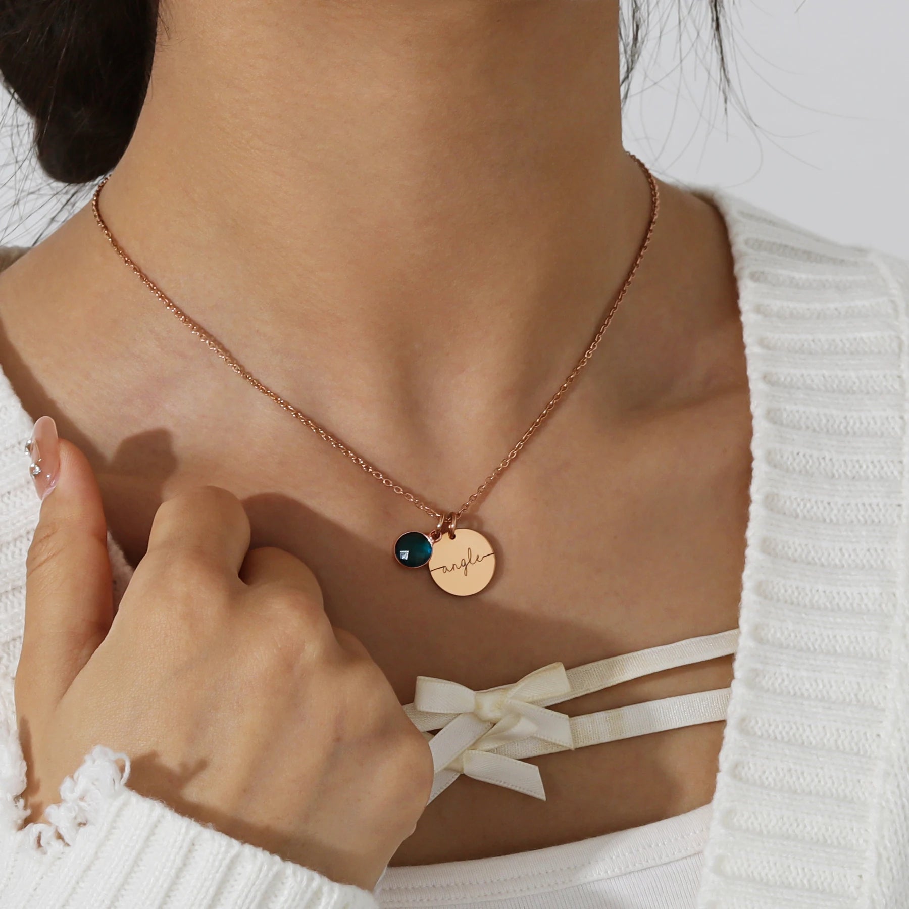 Collier médaillon personnalisé de couleur or rose avec prénom gravé et pierre de naissance, porté autour du cou.