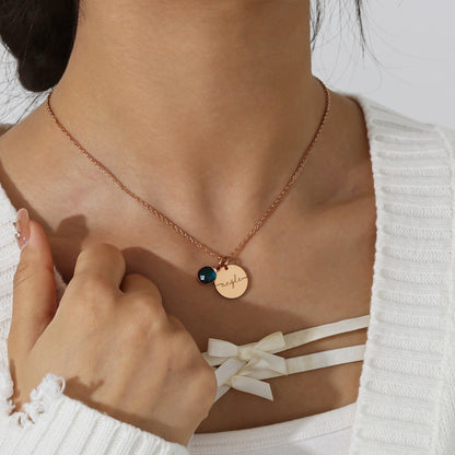 Collier médaillon personnalisé de couleur or rose avec prénom gravé et pierre de naissance, porté autour du cou.